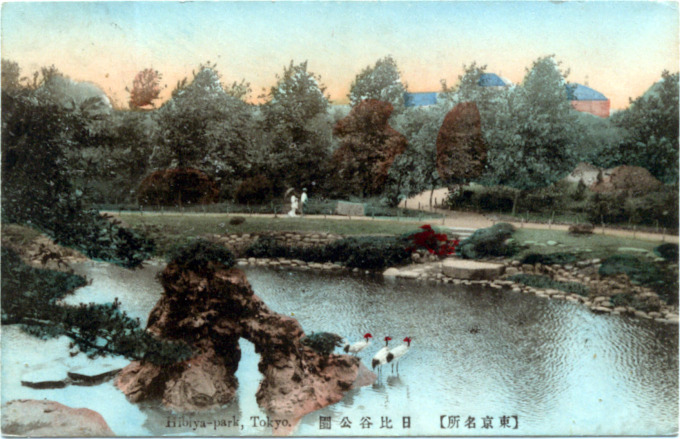 A couple walk the path around Hibiya Park's Japanese garden. In the distance, to the west, can be seen the rooftops of the various ministries along Sakuradamon-dori in the neighboring Kasumigaseki government district.